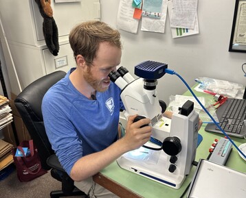 NC Fs Tucker Taylor studies ticks from the trail survey under a microscope to confirm species and quantities present